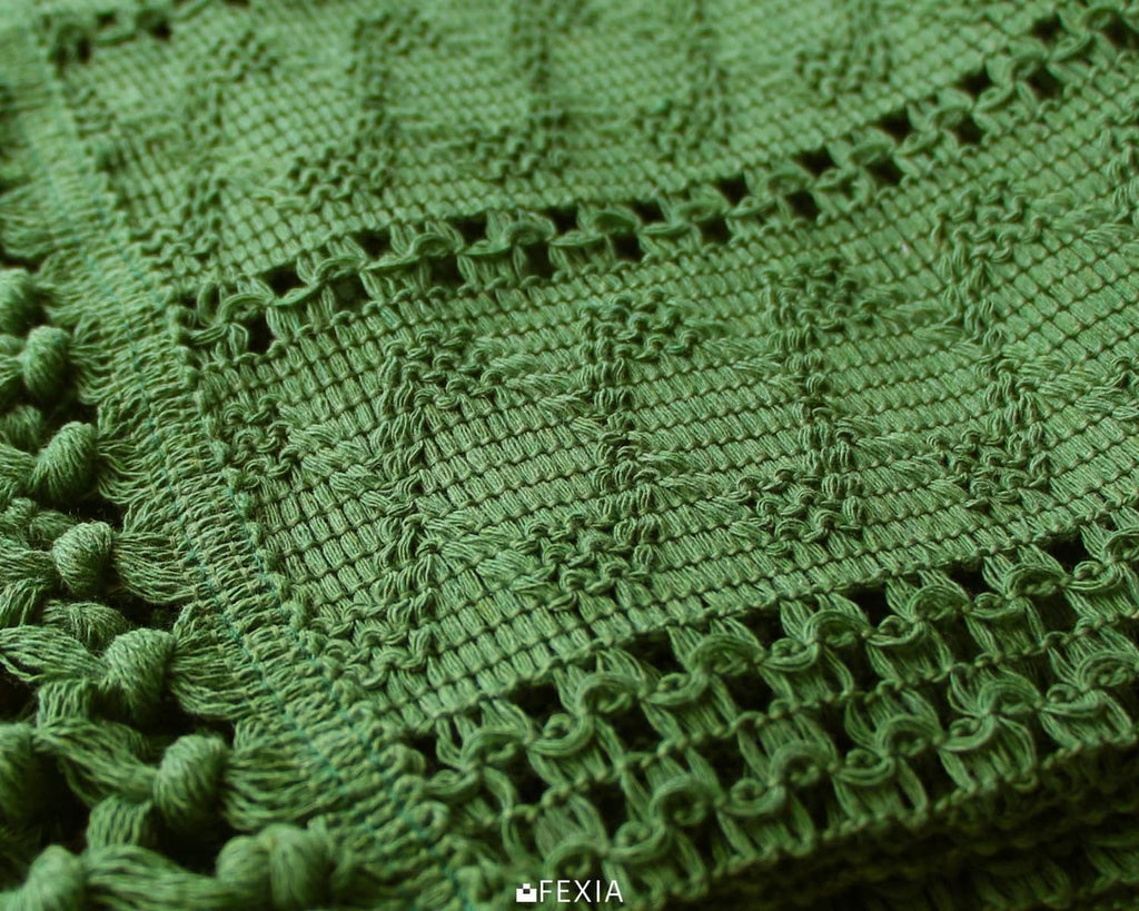 Green woven table runner fabric close-up with loop trim and fringe tassels.