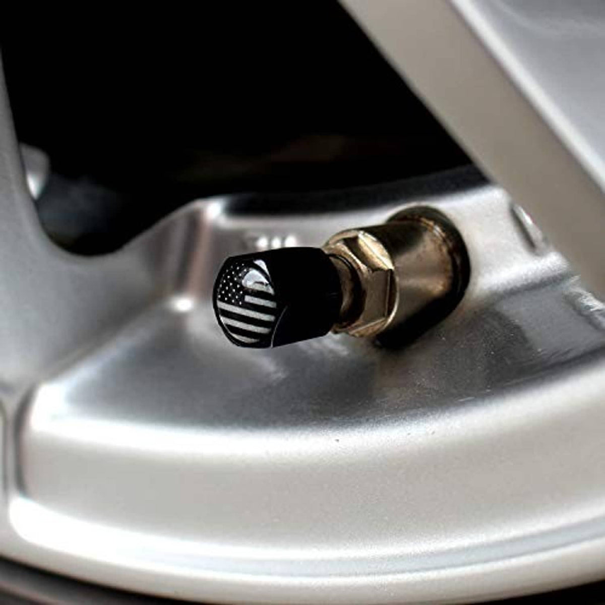 Black American flag valve cap with center opening on silver tire rim