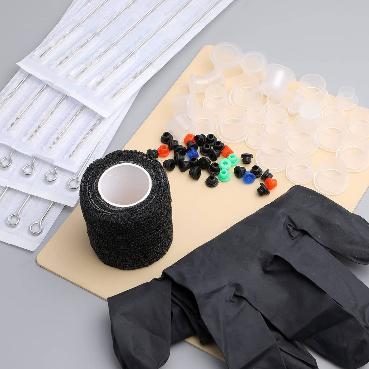 Tattoo kit with black gloves, black grip tape roll, and assorted needle caps