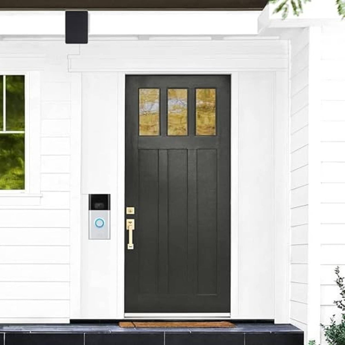 Video doorbell mounted beside a black front door on a white exterior wall
