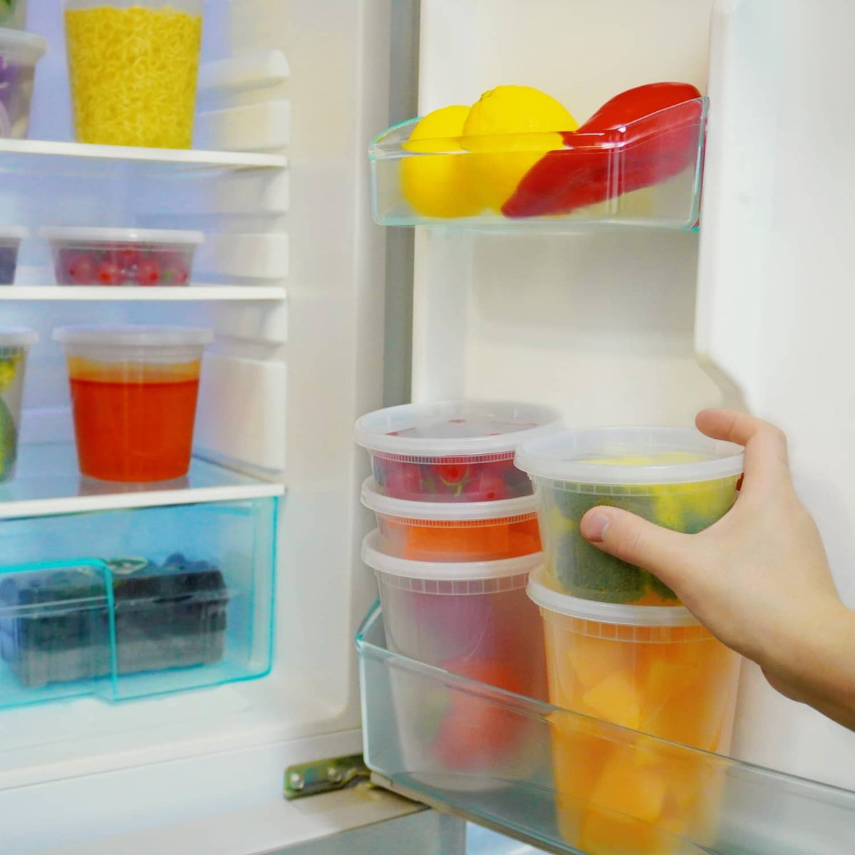 Hand placing clear plastic deli containers with lids into refrigerator for storage