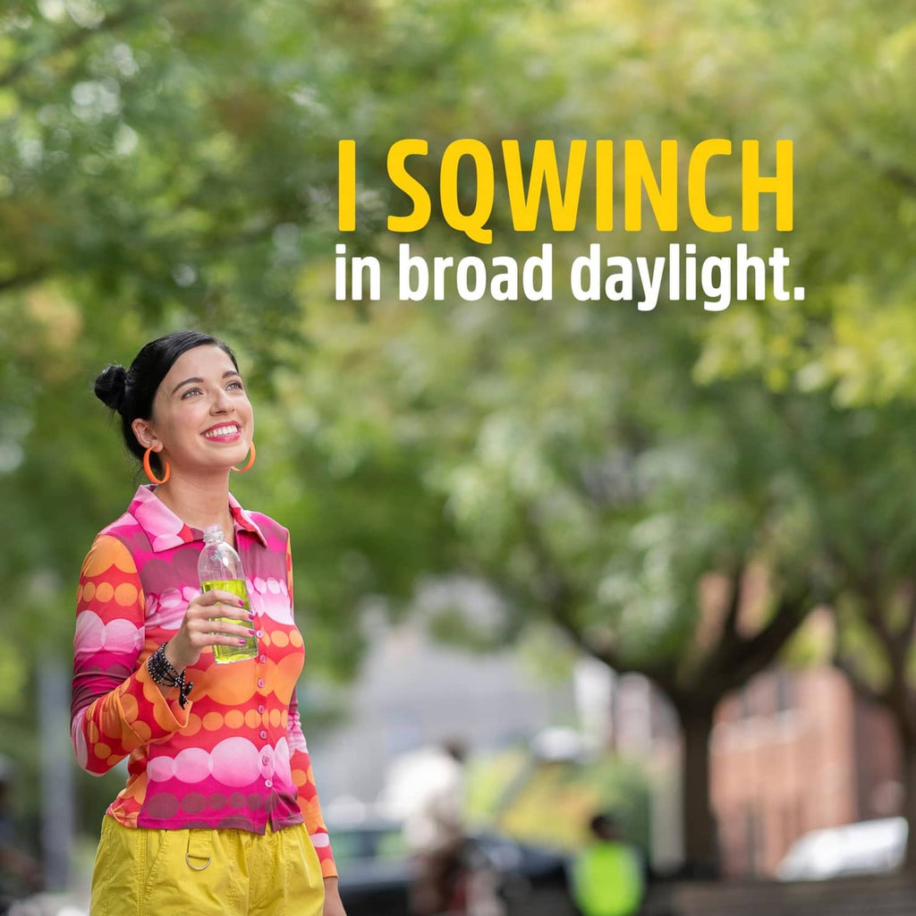 Woman holding yellow lemonade electrolyte drink, outdoor daylight