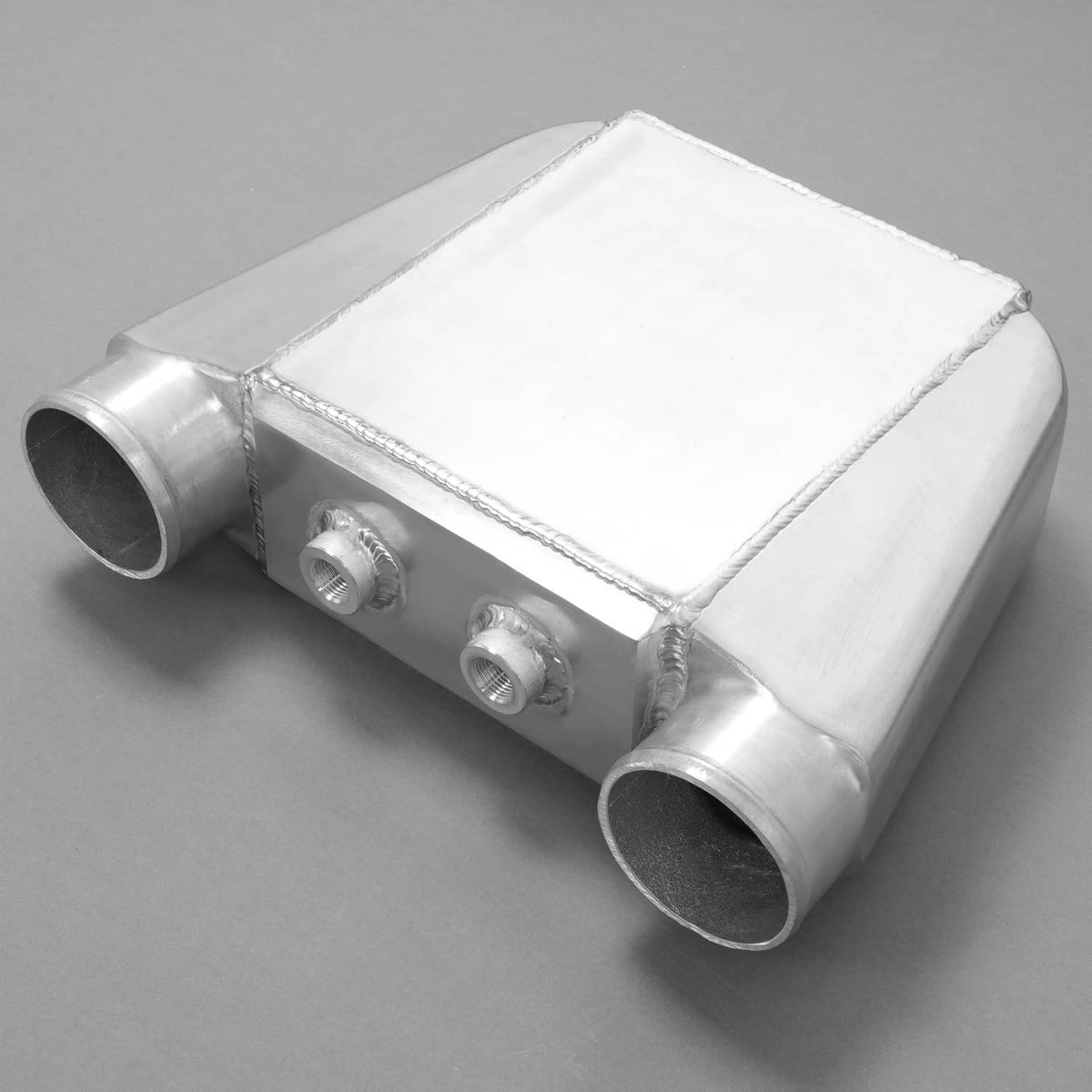 Aluminum water intercooler with end tubes and mounting ports, welded silver finish