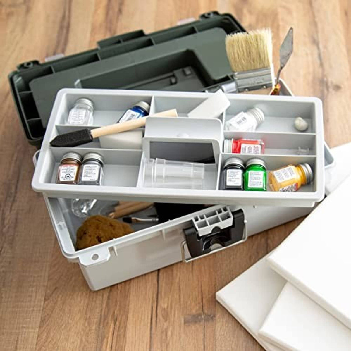 Grey tackle box open on wood table with organized bottles, jars, and tools