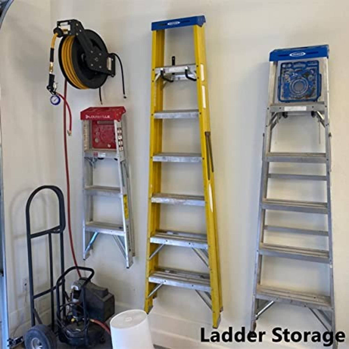 Black garage wall-mounted ladder storage hooks holding tools on a wall