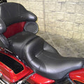 Black motorcycle passenger seat with contoured cushion and stitched seams, side view