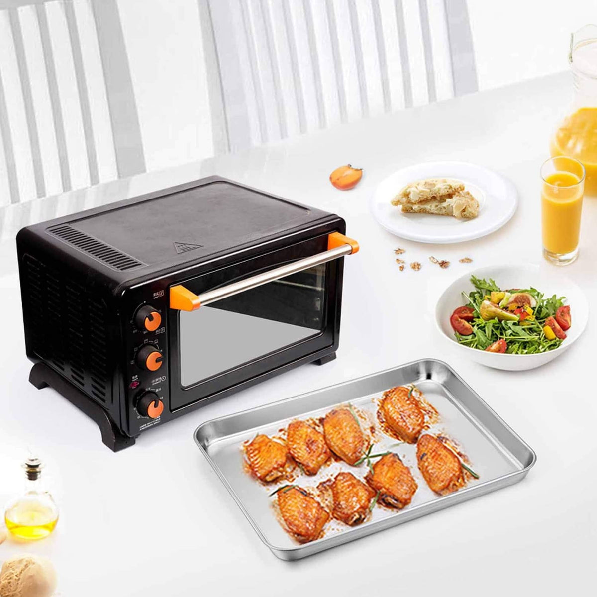 Stainless steel toaster oven tray holding cooked food, rectangular shallow pan