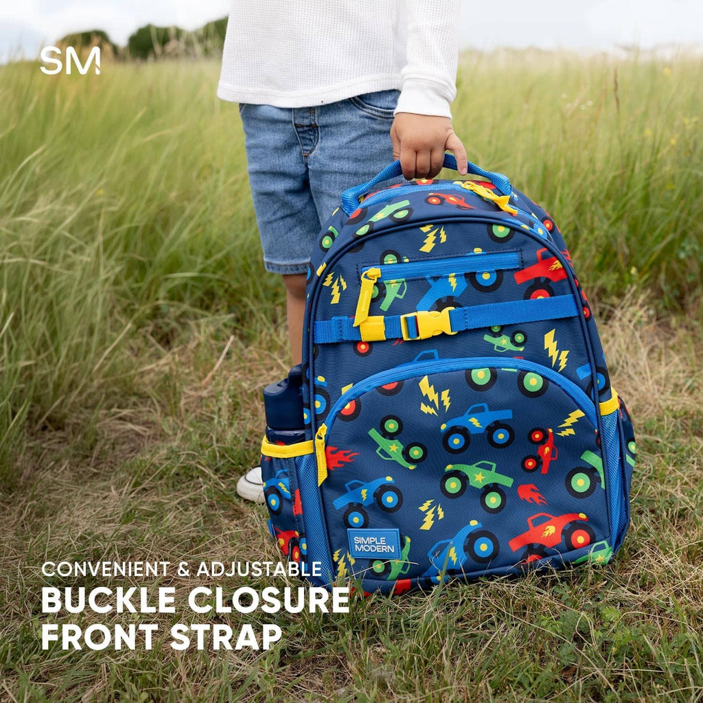 Toddler backpack with navy vehicle print and front buckle closure strap on grass