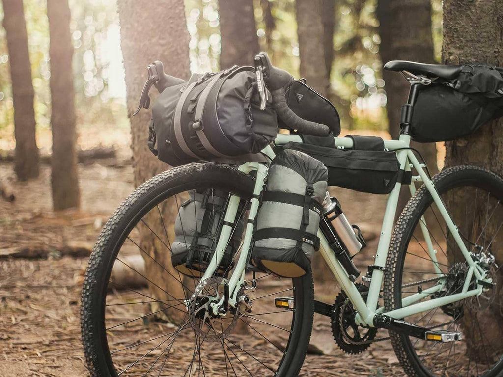 Two black cargo bags mounted on trail bike frame with straps