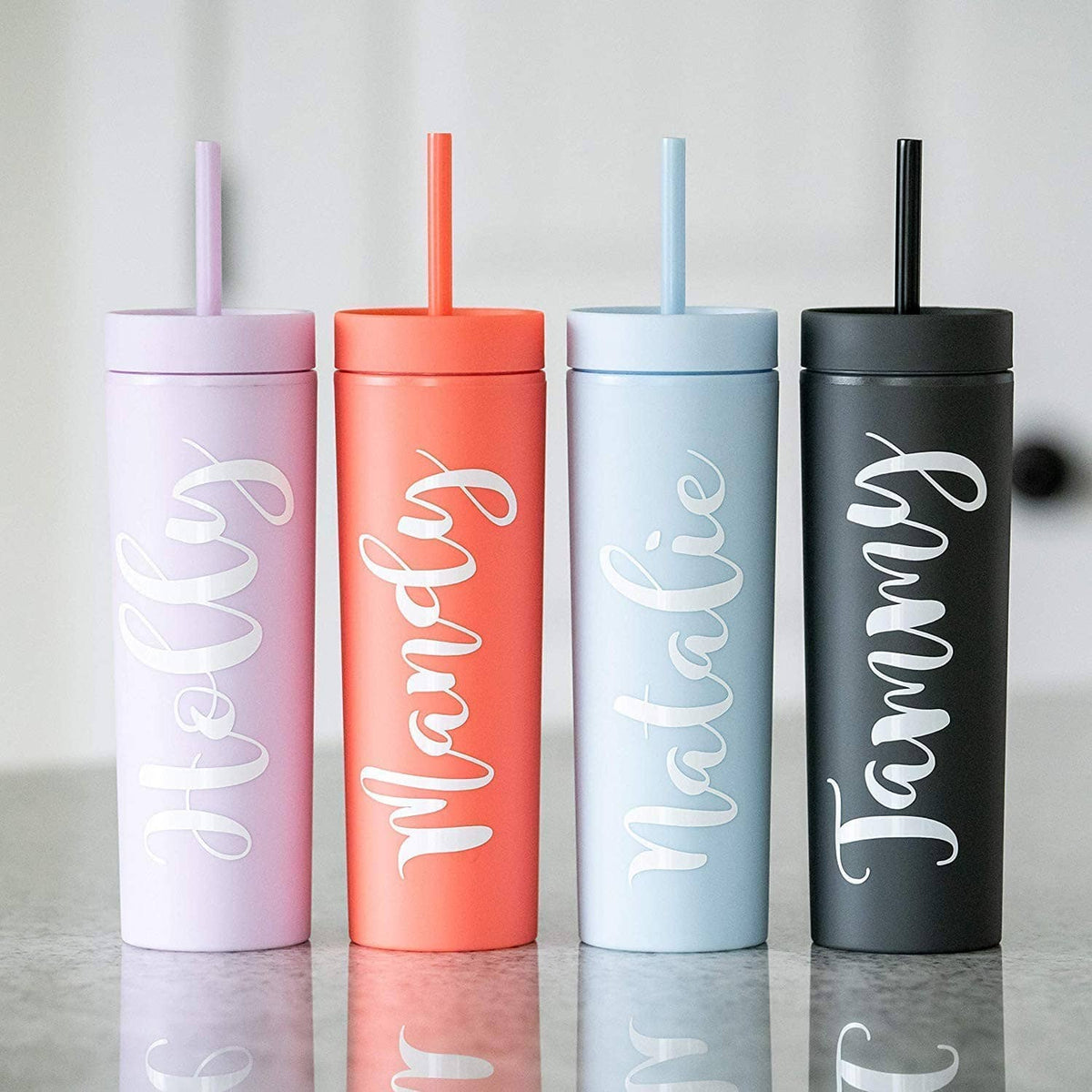 Set of skinny tumblers with lids and straws in lavender, coral, light blue, and black