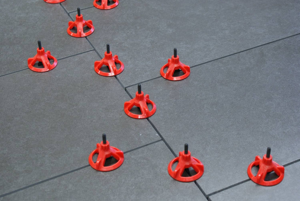 Tile leveling system red baseplates with threaded posts on tile floor