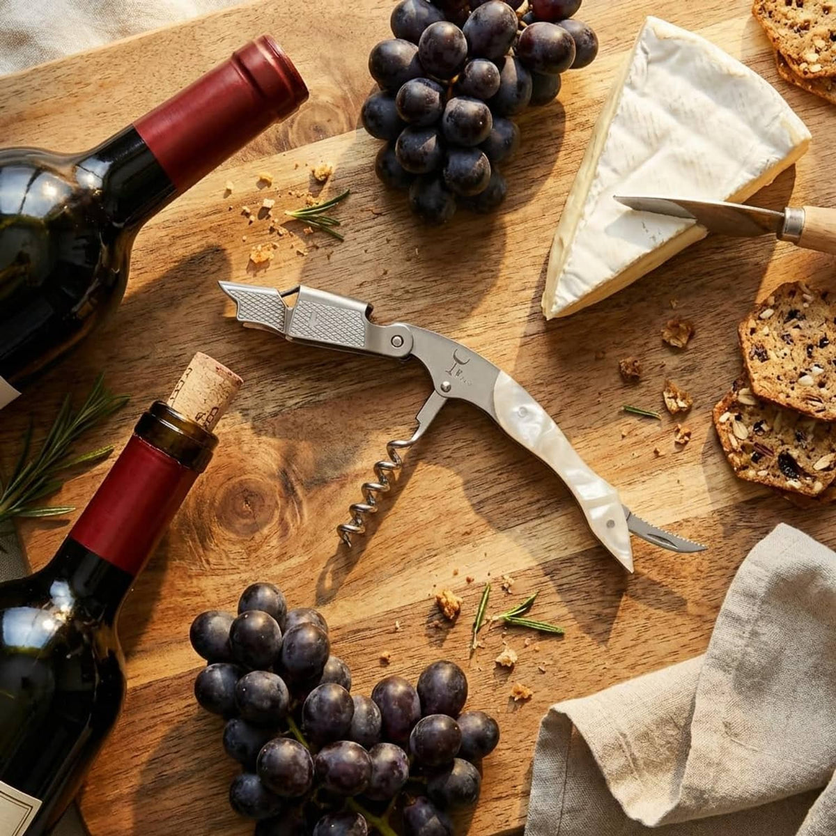 Emerald green-handled wine corkscrew on a wooden board with grapes nearby.