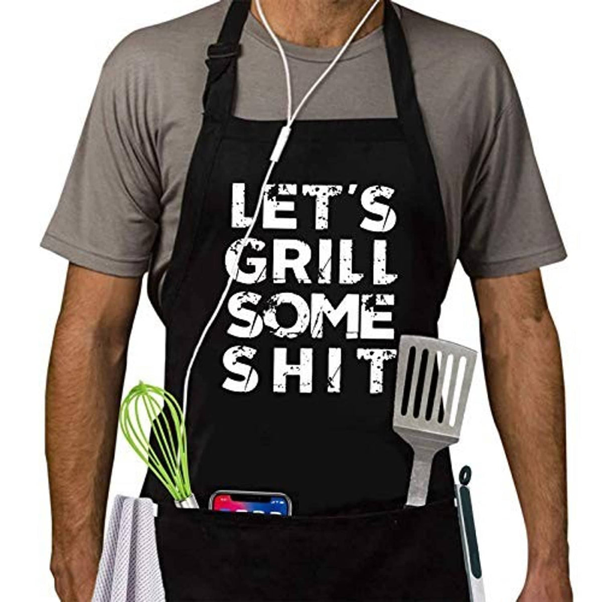 Black BBQ apron worn by man, "LET'S GRILL SOME SHIT" text with hanging grill utensil