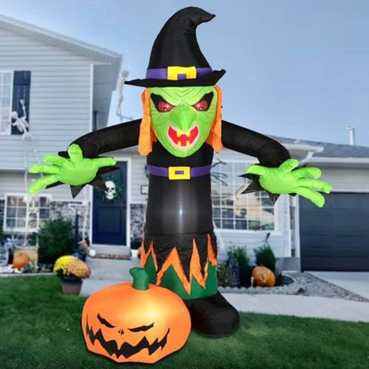 Inflatable Halloween witch decoration with green face and orange jack-o'-lantern base