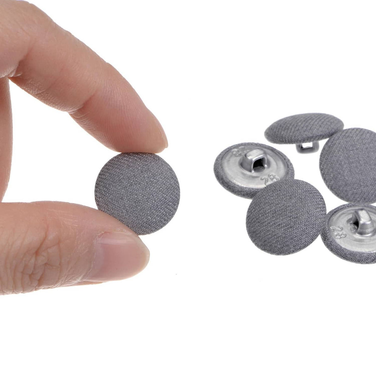 Grey fabric-covered button with metal shank, shown front and back detail