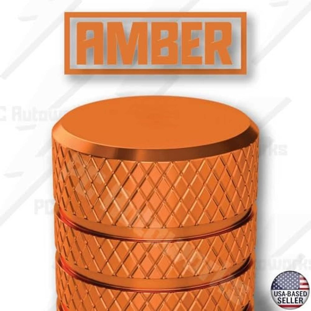 Close-up of amber orange anodized valve stem cap with ridged grip and black opening