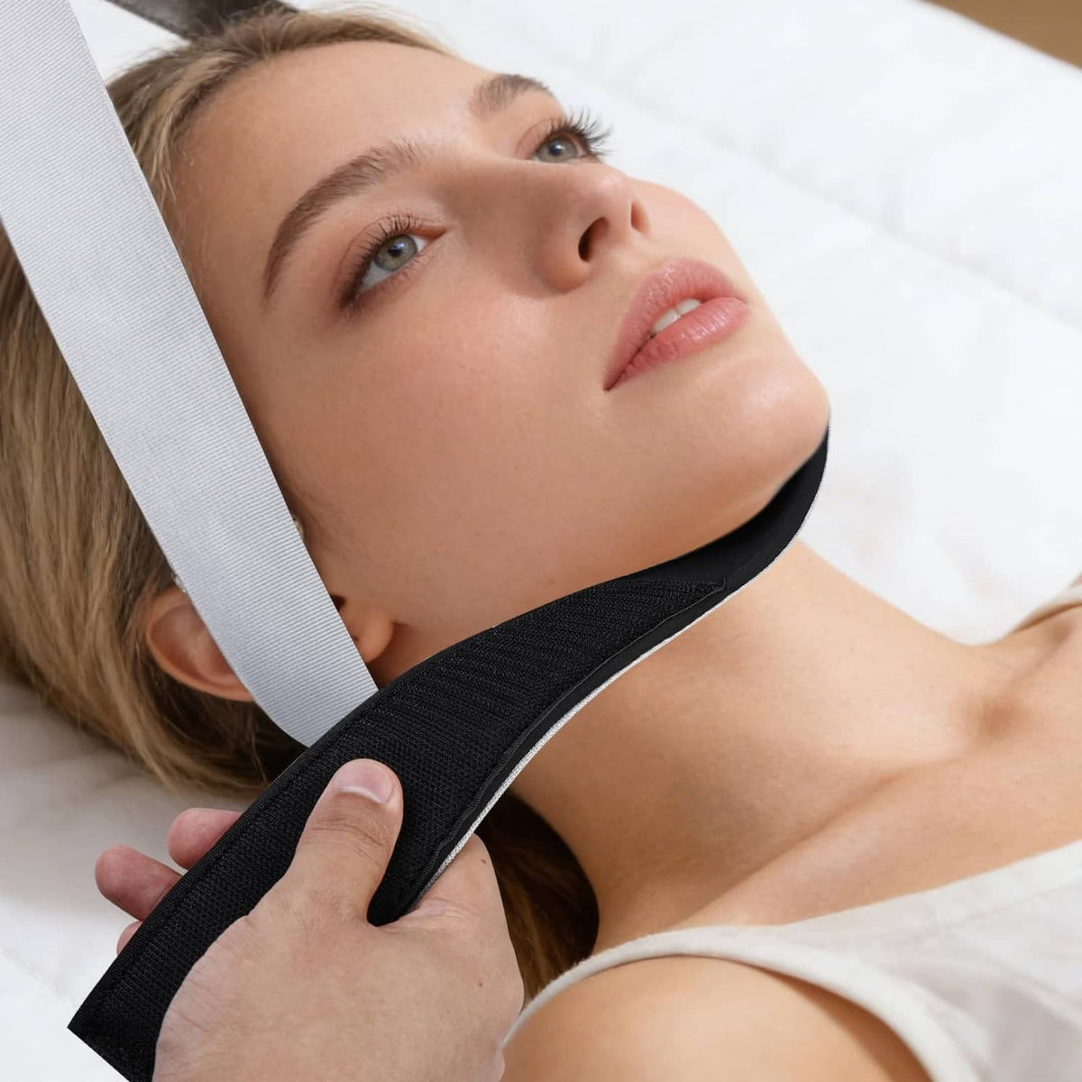 Neck traction strap with black neck support and light gray strap; hand adjusting