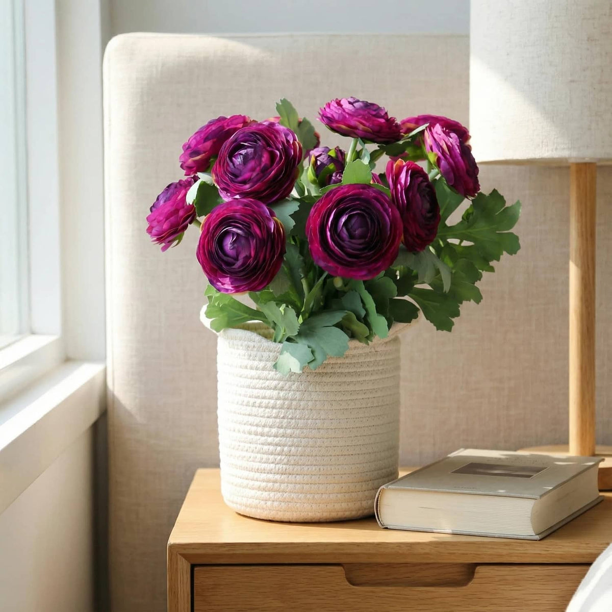Purple artificial ranunculus bouquet in textured white pot with green foliage