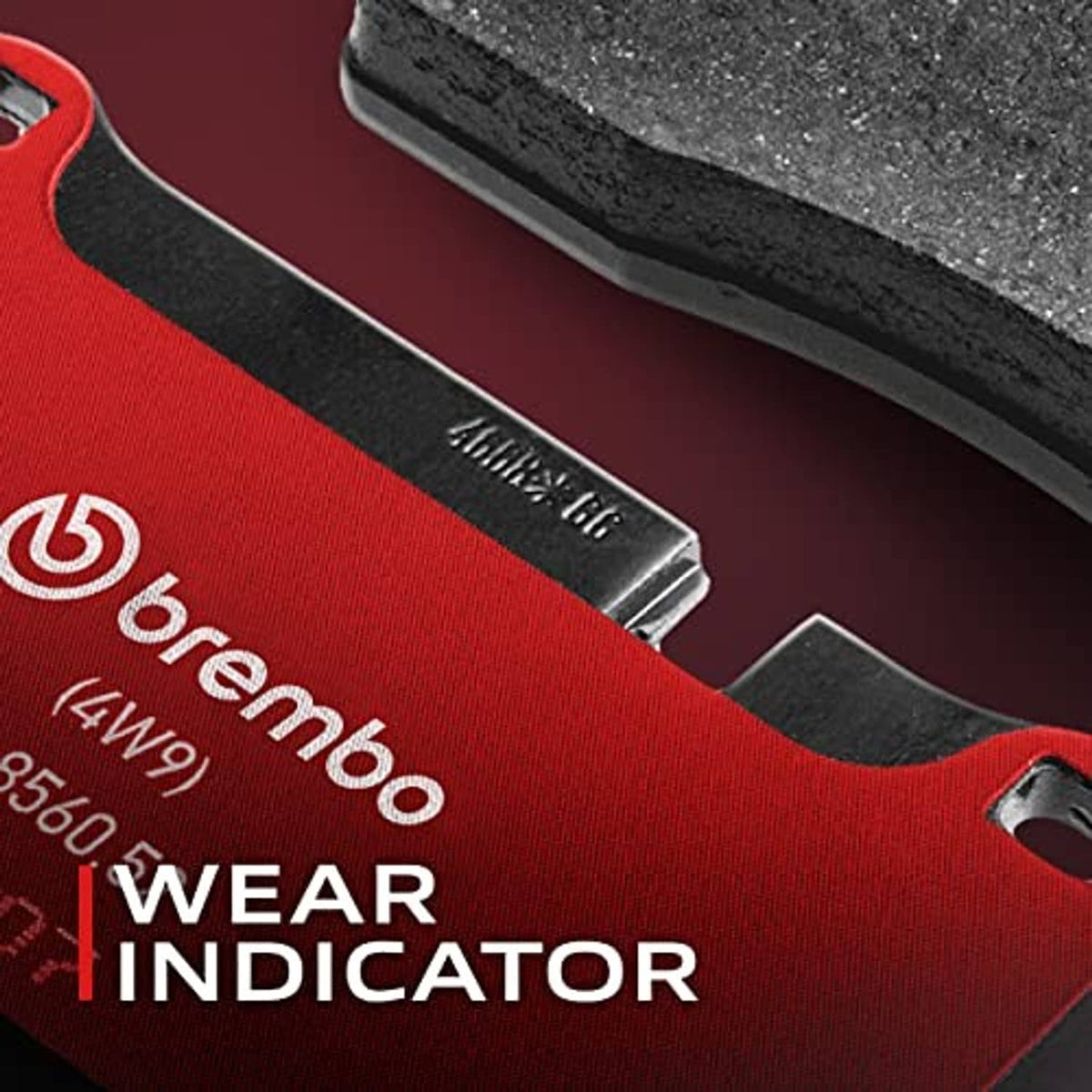 Ceramic brake pad close-up with red wear indicator strip on gray backing