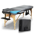 Portable massage table with gray frame, blue memory-foam top, wooden legs, armrests