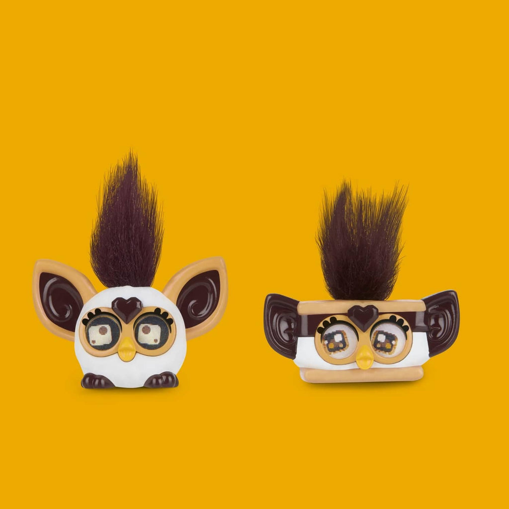 Two brown Furby minis heads with yellow beaks, goggles, and tall dark or blond mohawks