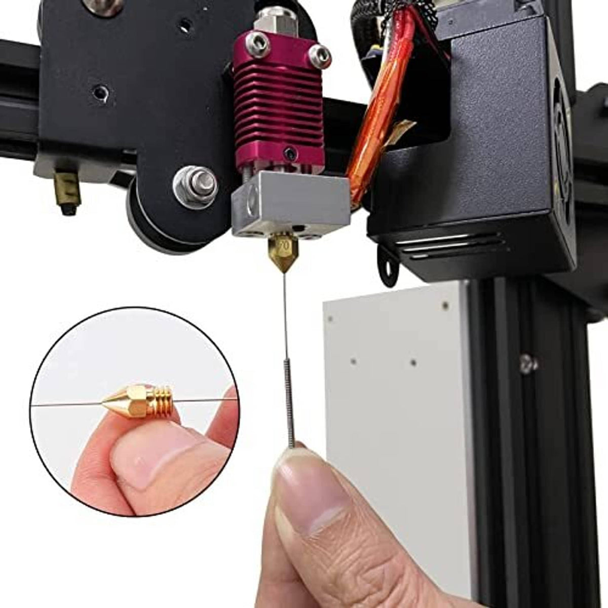 Stainless cleaning needle inserted into printer extruder nozzle; hand-held close-up