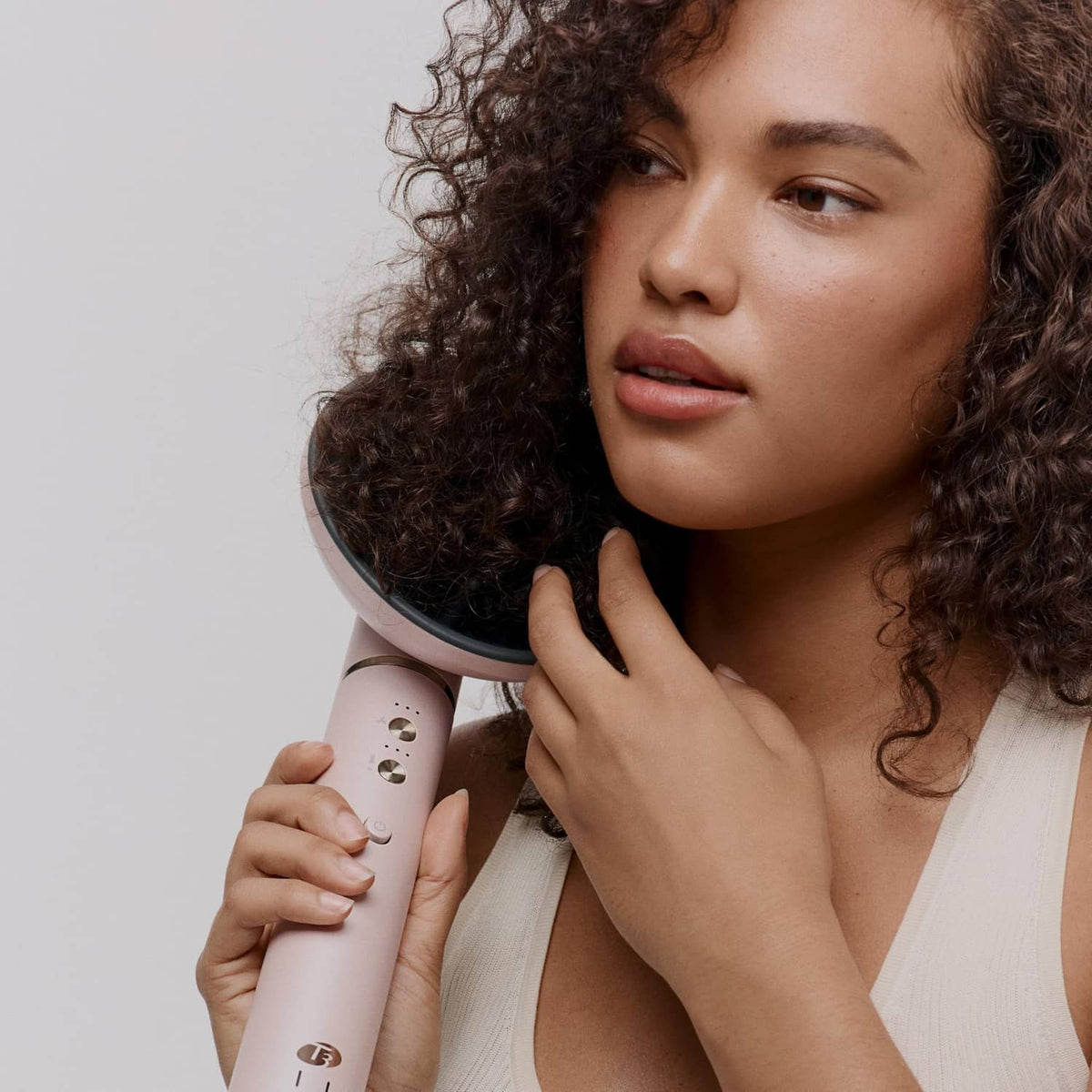 Blush hair diffuser tool held near curly hair for styling