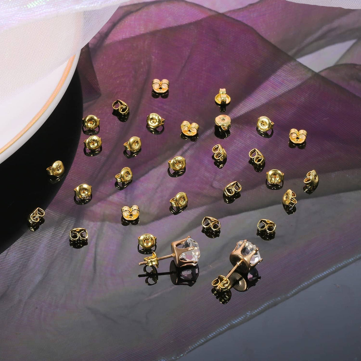 Gold butterfly earring backs scattered on fabric