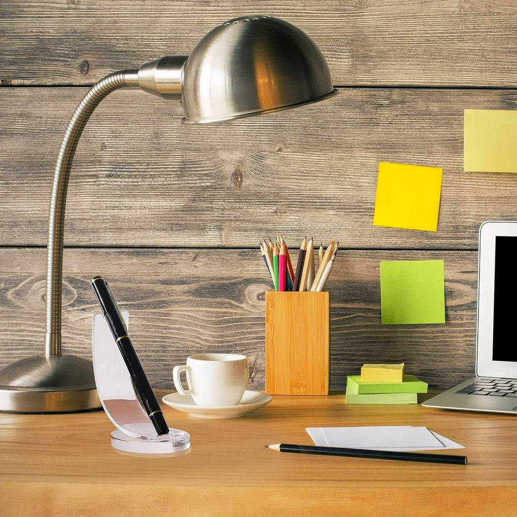 Clear acrylic pen holder holding black pen with gold accents on desk surface