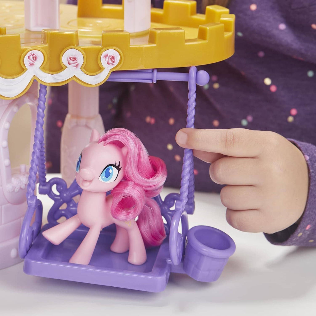 Pink pony figure seated on purple swing platform, with hand adjusting the rail