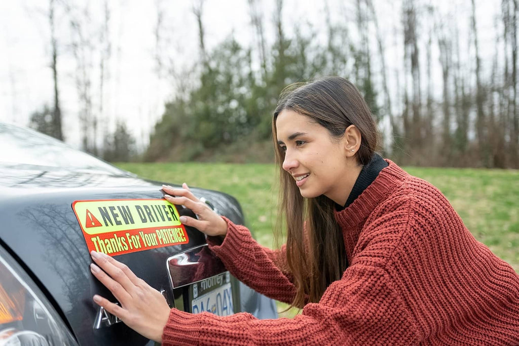 Magnetic “New Driver” sign being placed by a person on a parked car door.