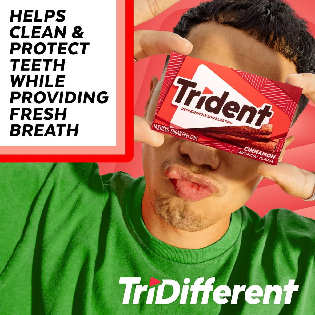 Trident cinnamon sugar-free gum pack held near mouth, red package