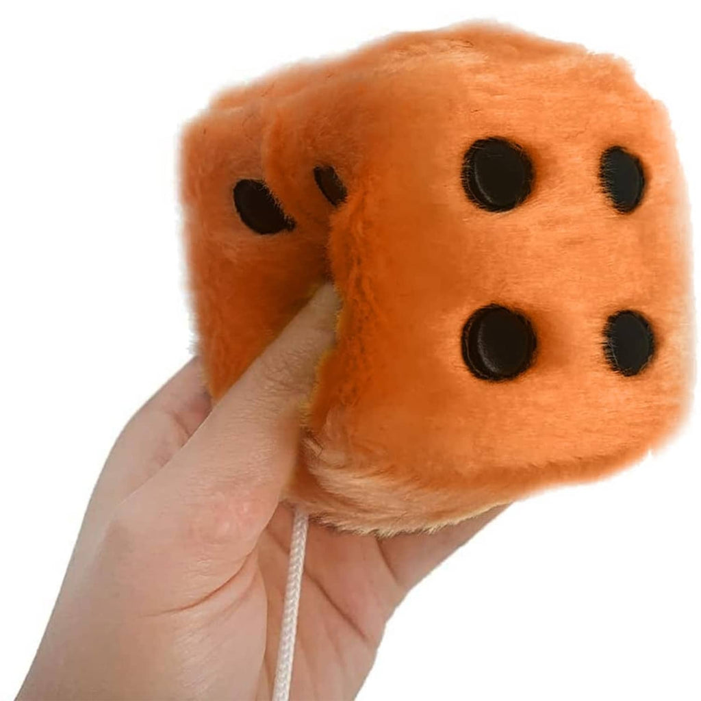 Orange-brown fuzzy plush dice cube with black dot face, held by hand