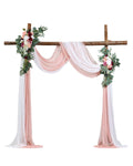 Pink faux wedding arch with floral corner pieces and flowing sheer drapes
