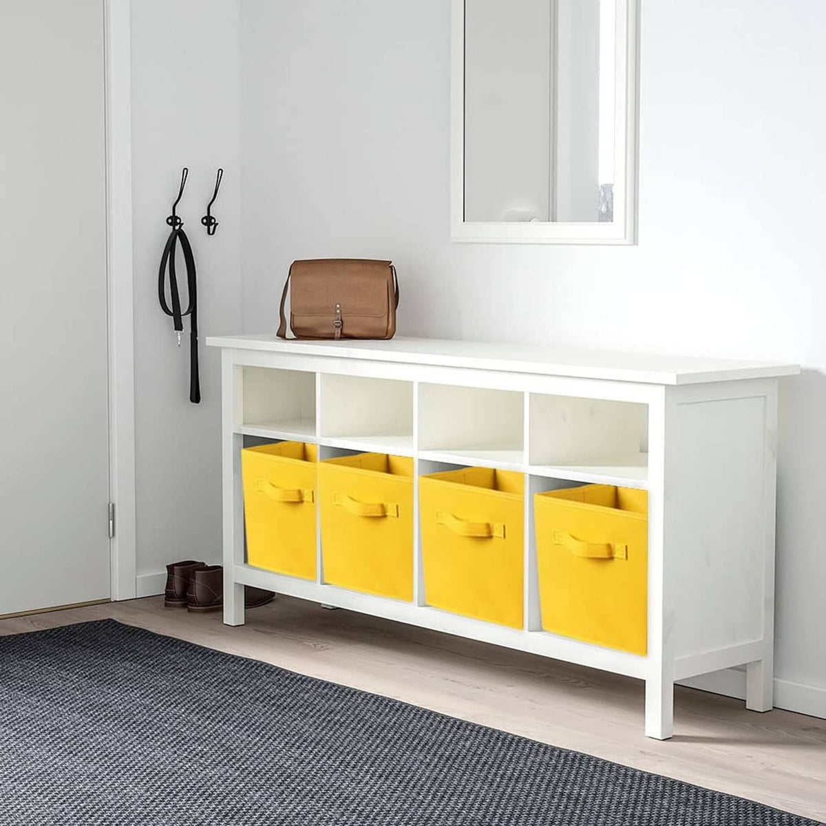 Yellow fabric storage bins with handles under a white storage console.