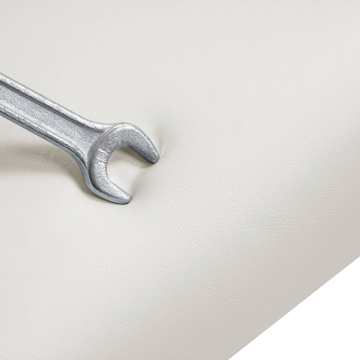 Close-up of gray metal wrench-like hardware on white cushion surface