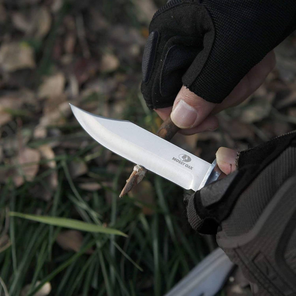 Hand holding a Bowie knife with wood handle and black sheath