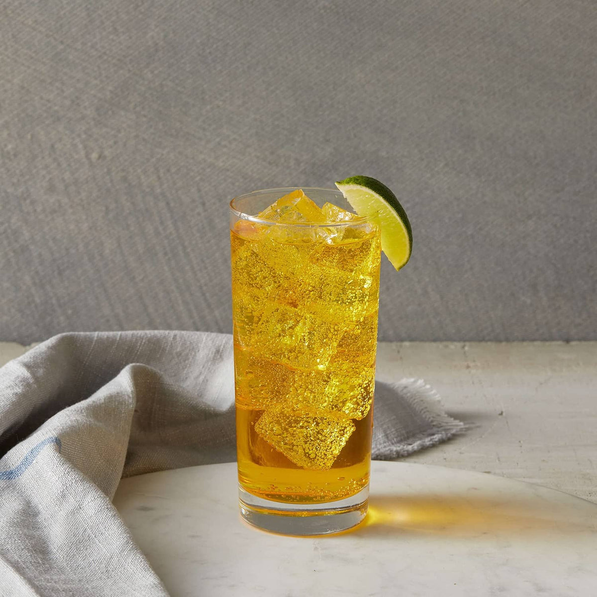 Passion fruit syrup cocktail in tall glass with lime wedge and ice