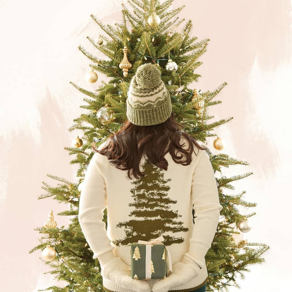 Person holding a wrapped gift in front of a decorated Christmas tree