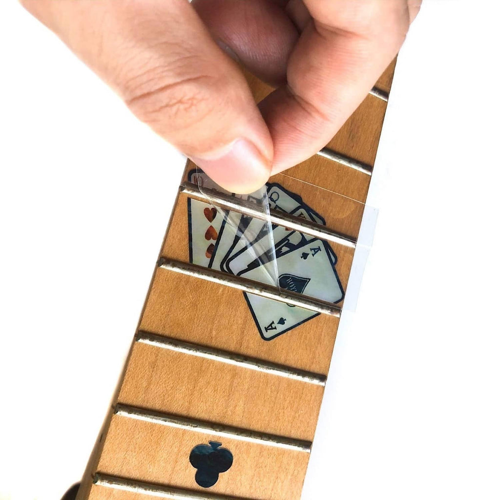 Hand applying guitar fretboard inlay sticker to wood fret markers