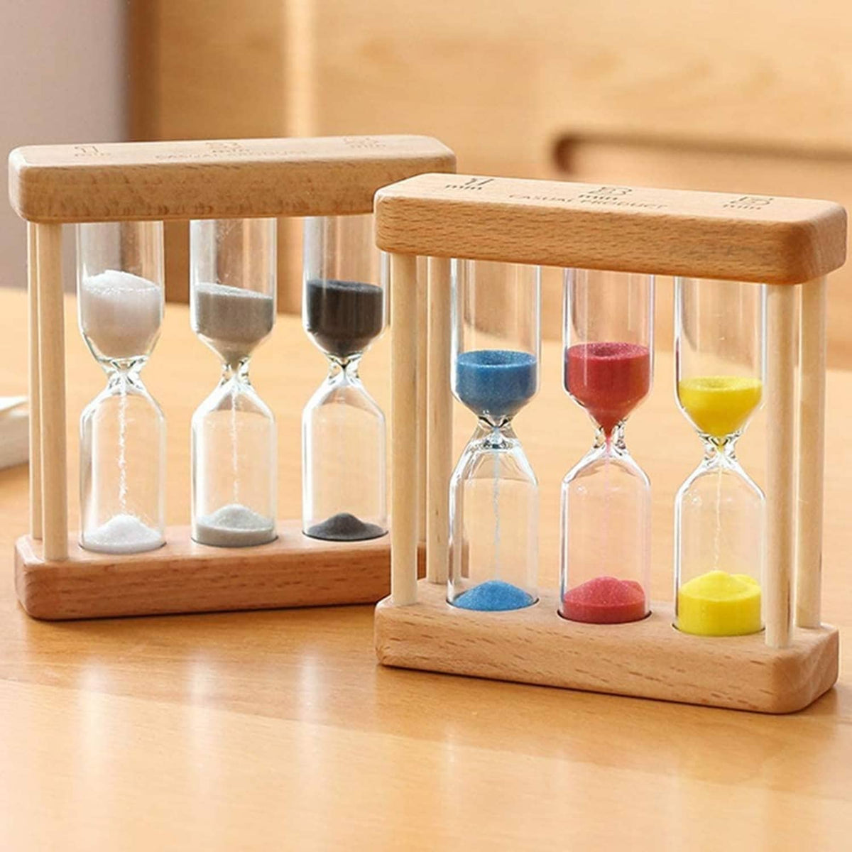 Two wooden hourglass timers: one gray sand, one with blue, red, and yellow sand