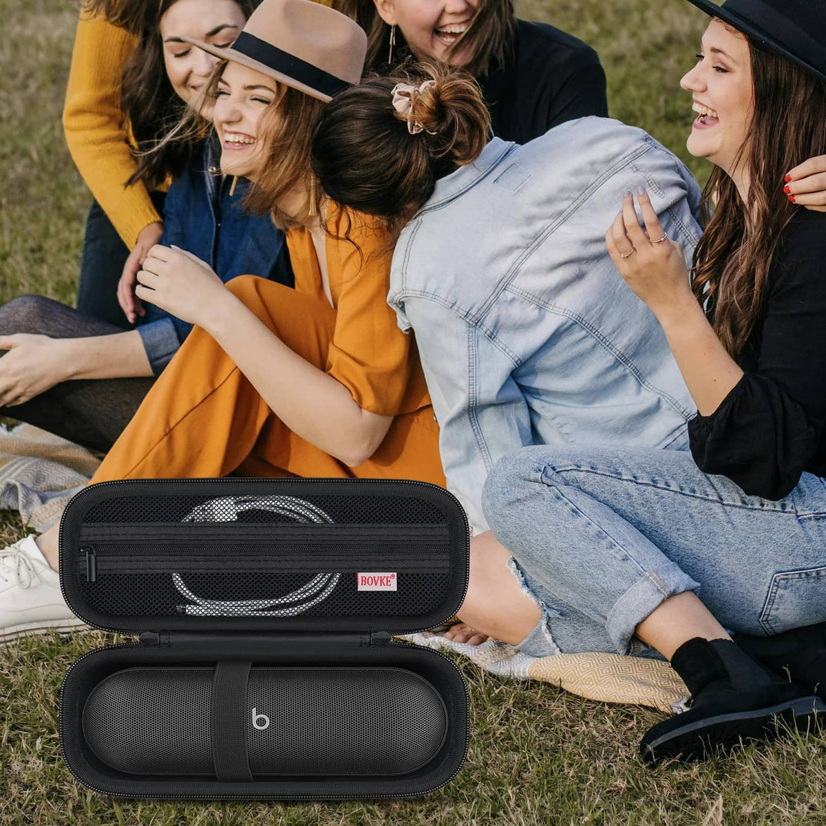 Black zippered carrying case open with portable speaker inside on outdoor grass