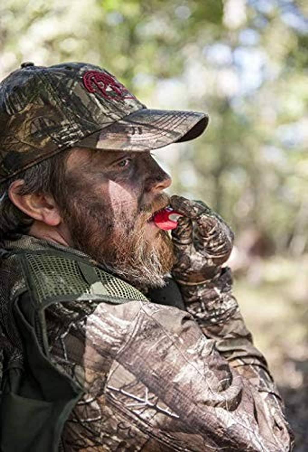 Red foam turkey mouth call held to hunter’s lips under camo