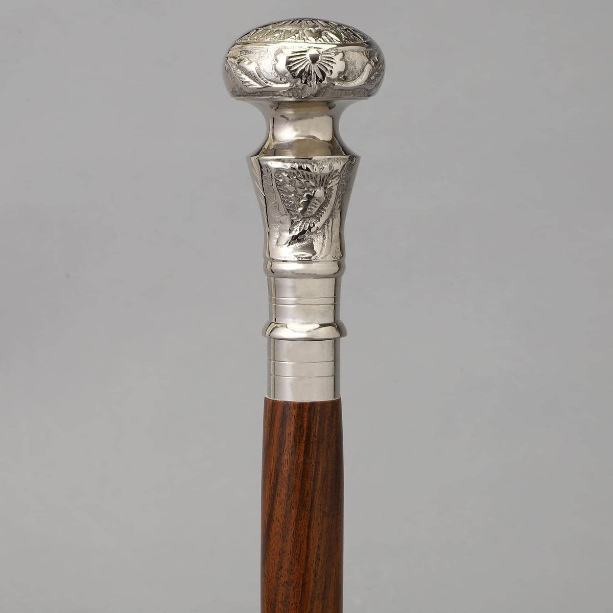 Silver decorative handle on brown wooden walking cane with polished barrel rings