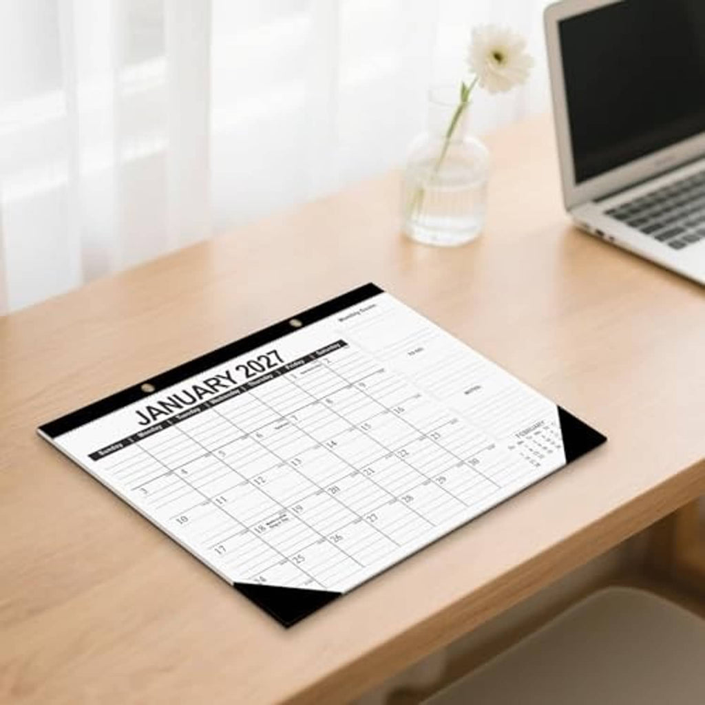 January 2027 desk calendar lying on wooden desk with black corner design
