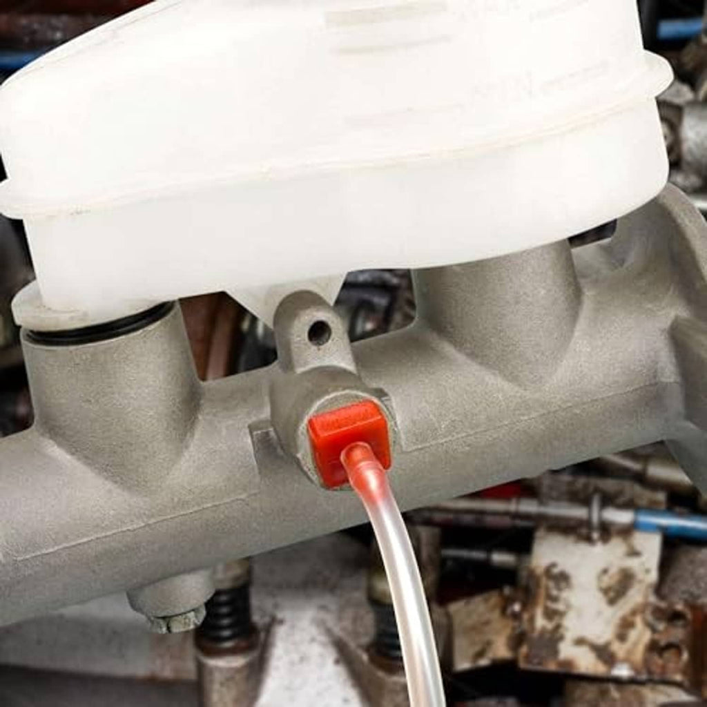 Close-up: brake master cylinder outlet with clear hose and red push-in bleeder fitting