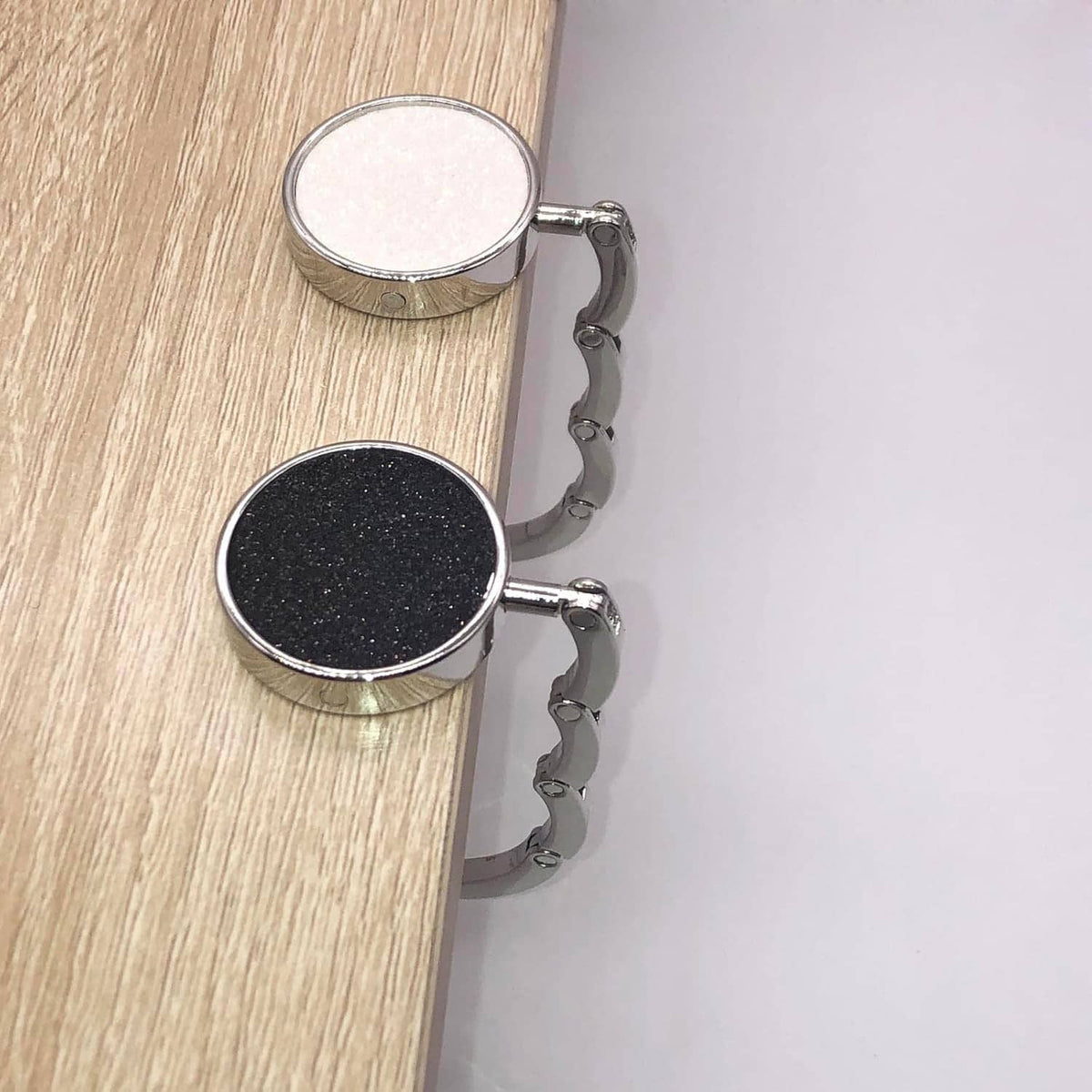 Foldable purse hook set with two silver clips and glitter pads in white and dark gray
