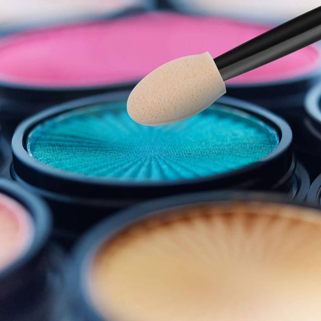 Close-up sponge tip makeup brush dipping into turquoise eyeshadow in a compact