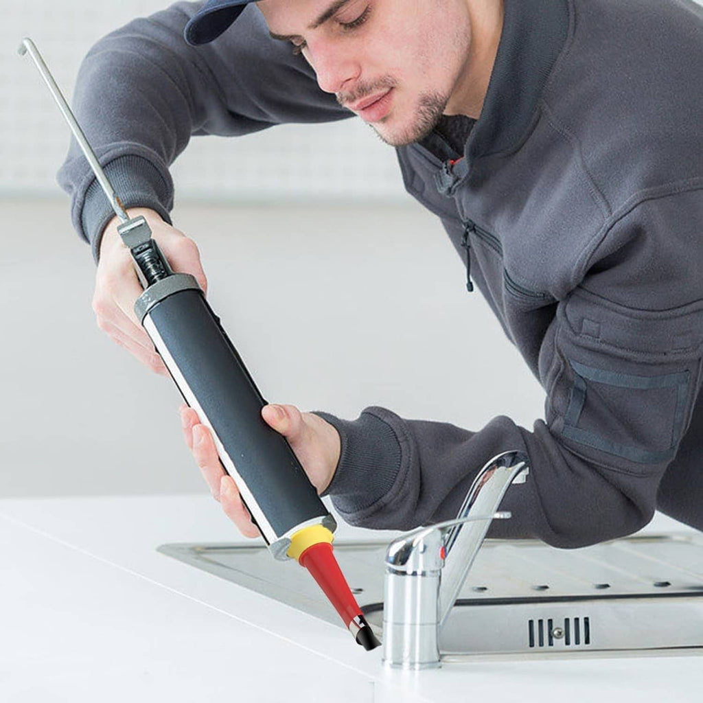 Person caulking a countertop seam with a handheld caulk gun and red finisher nozzle tip