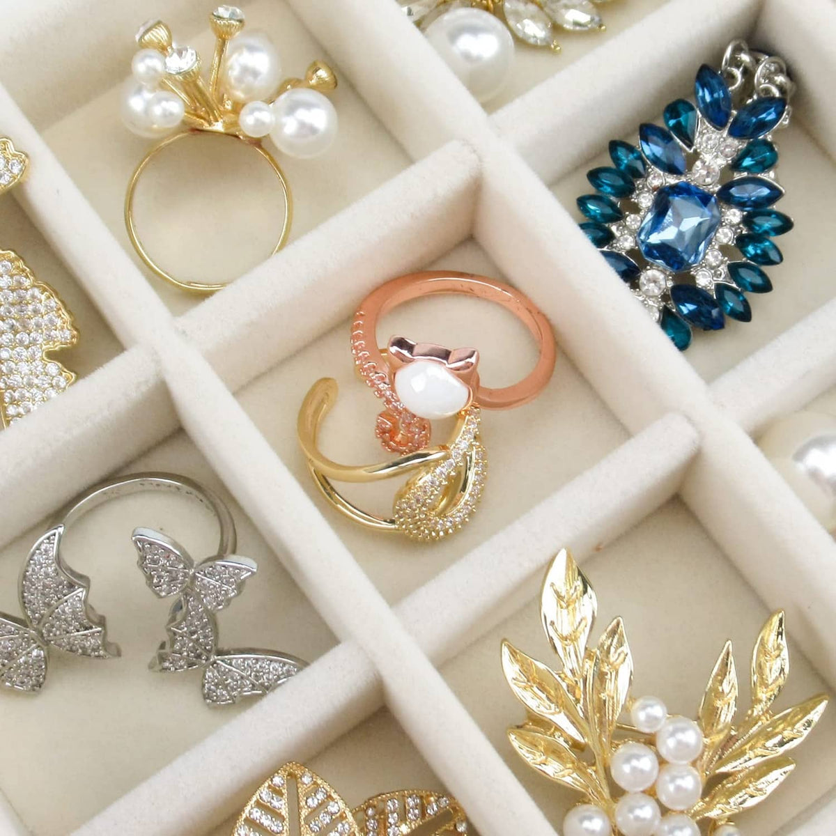 Beige compartment insert holding assorted earrings in a clear drawer grid